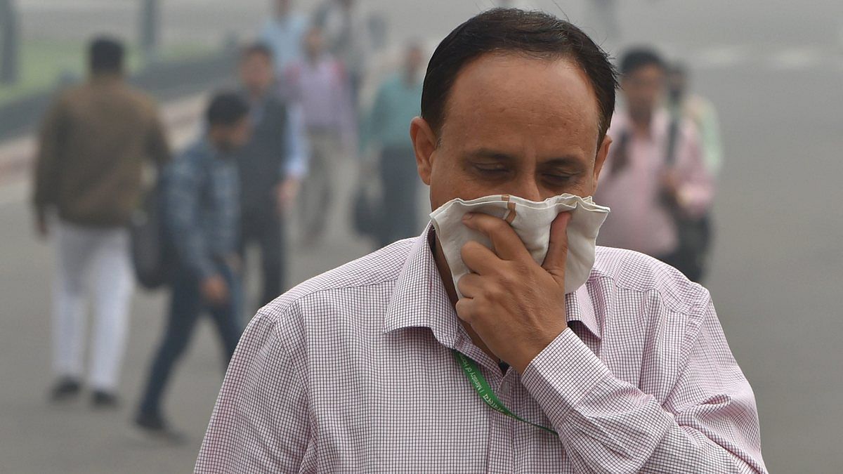 A pedestrian covers his face with a handkerchief for protection against air pollution, in New Delhi