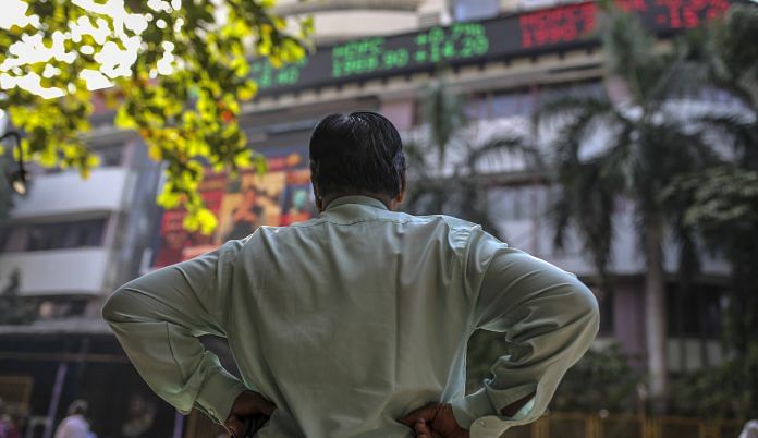 A man stands in front of an electronic ticker board showing stock information figures outside the Bombay Stock Exchange (BSE) in Mumbai