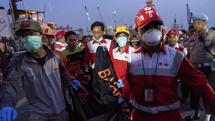 Search and rescue team members carry a body recovered from the crash | Rony Zakaria/Bloomberg