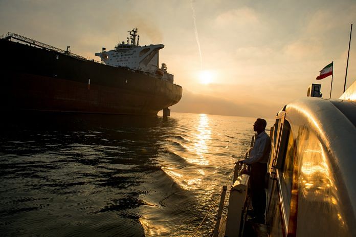 A support vessel flying an Iranian national flag sails alongside the oil tanker 'Devon' as it prepares to transport crude oil to export markets in Bandar