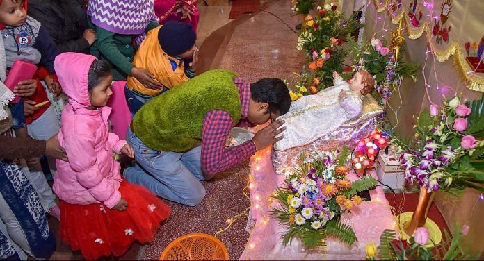 A devotee kisses a statue of baby Jesus during Christmas celebration at a Catholic church, in Patna