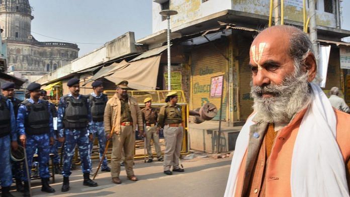 A sadhu walks along a road as police and RAF personnel keep vigil, on the anniversary of Babri mosque demolition, in Ayodhya