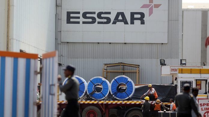Signage for Essar Steel Ltd. is displayed as workers load items onto a truck at the company's Pune Facility in Maharashtra