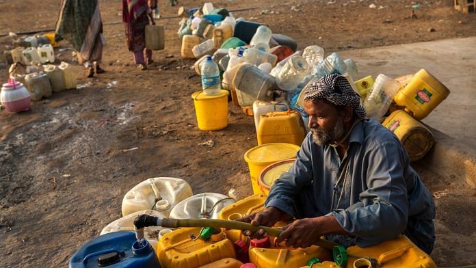 A man fills containers with water in Karachi | Asim Hafeez/Bloomberg