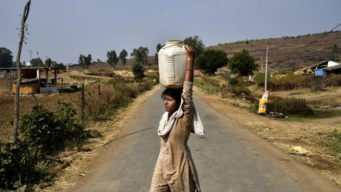 A woman carrying water on her head crosses a road in Bhopal District | Anindito Mukherjee/Bloomberg