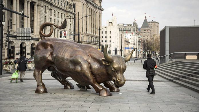 Pedestrians walk past the Bund Bull statue in Shanghai