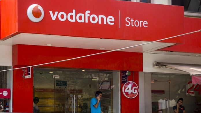 Customers talk on mobile phones outside a Vodafone India Ltd. store | ThePrint,in