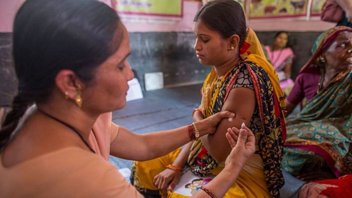 A health worker immunises a pregnant woman at a health centre in Aurangabad, India