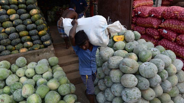 An vendor carries a sack of pumpkins at a wholesale market in Chennai