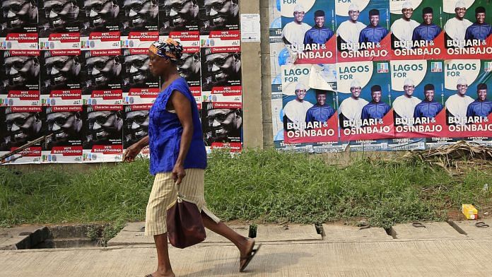 A woman walk pass campaign posters of Muhammadu Buhari, Nigeria's president, and candidate of the ruling All Progressives Congress (APC) party, in Lagos Nigeria