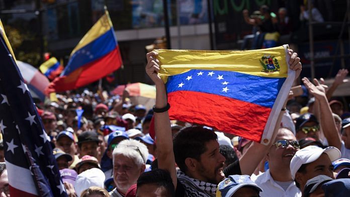 Opposition supporters wave Venezuelan flags during a rally against Nicolas Maduro, Venezuela's president | Carlos Becerra/Bloomberg