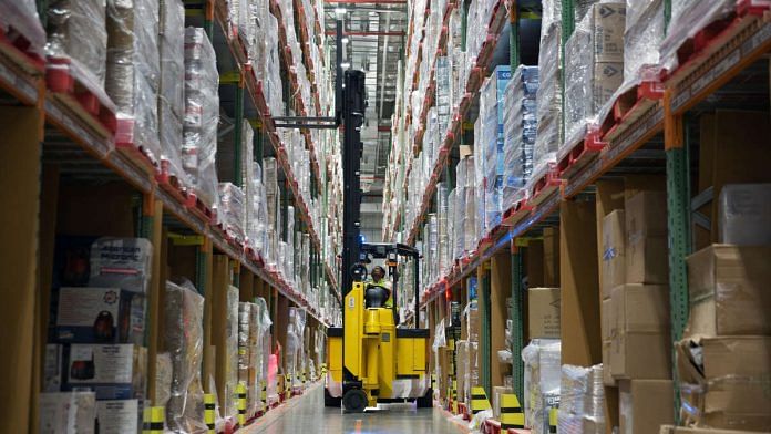A worker uses a forklift to remove a pallet of goods from a storage rack in an aisle at the Amazon Inc. fulfillment center in Bengaluru