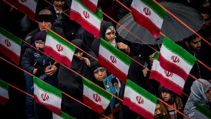 Iranians march beneath Iranian national flag design bunting during celebrations marking the 40th anniversary of the Islamic revolution in Tehran, Iran| Photo: Ali Mohammadi | Bloomberg