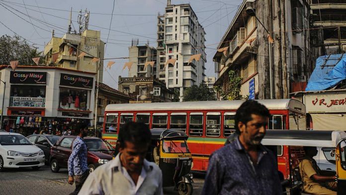 Pedestrians and traffic move past buildings in Mumbai