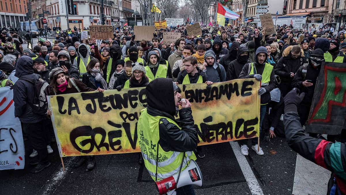 Demonstrators wearing yellow vests (Gilets jaunes) march behind a large banner during a protest in Toulouse, France
