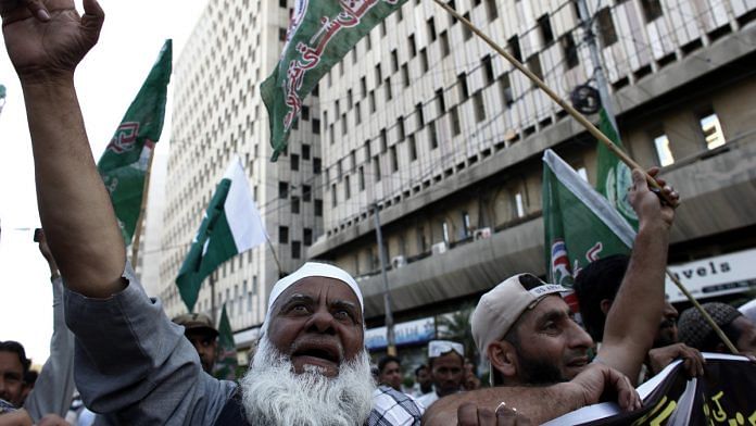 Demonstrators wave flags during an anti-India protest in Karachi, Pakistan