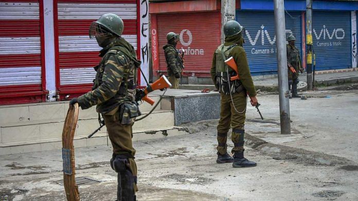 Security personnel stand guard along a road during restrictions in Downtown Srinagar