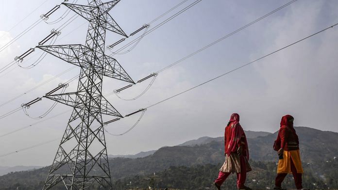 Woman walk past a transmission tower in Jammu and Kashmir | Dhiraj Singh/Bloomberg