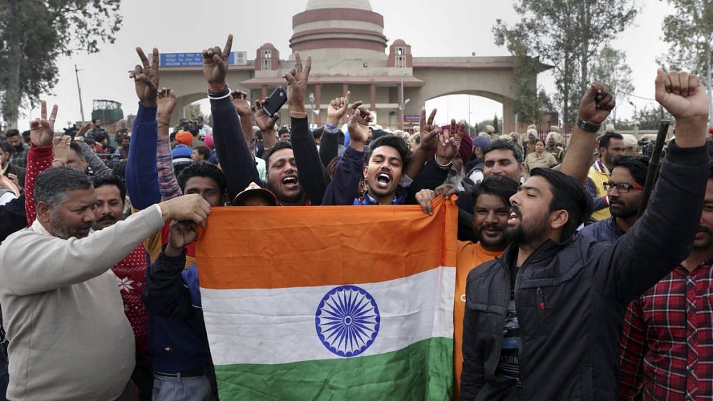 People celebrate with a Tricolour as they wait for the arrival of IAF pilot Wing Commander Abhinandan Varthaman at Attari-Wagah border near Amritsar | PTI photo