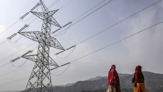 Woman walk past a transmission tower in Rajouri district, Jammu and Kashmir |Dhiraj Singh/Bloomberg