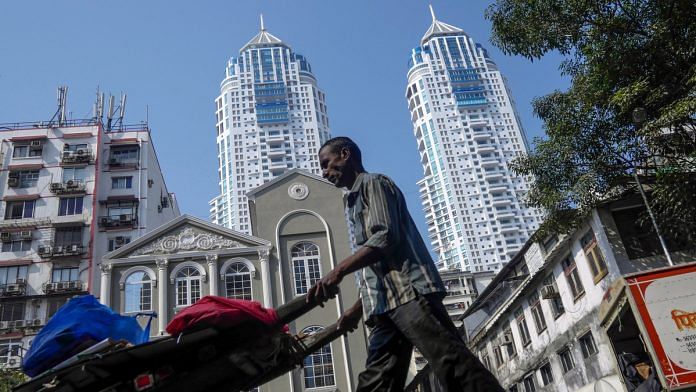 A man pushes a cart past the Imperial, a twin-tower residential skyscraper complex developed by S D Corp. | Dhiraj Singh |Bloomberg