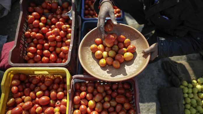 A vendor fills a bowl with tomatoes at a vegetable market