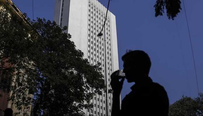 A man drinks tea as he walks past the Reserve Bank of India (RBI) headquarter building in Mumbai