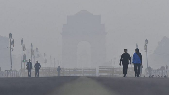 Pedestrians walk past the India Gate monument shrouded in smog in New Delhi.