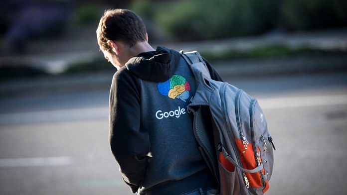 A pedestrian wearing a sweatshirt with a Google Inc. logo waits for a bus in front of the company's headquarters in Mountain View, California, U.S