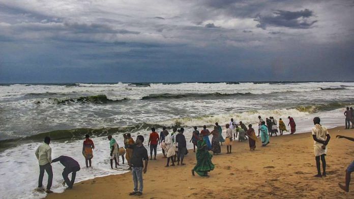 Villagers at the beach as dark clouds hover above the sea ahead of cyclone 'Fani'