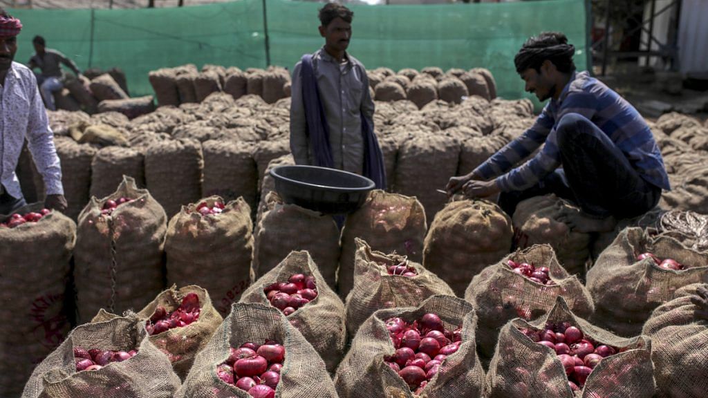 A worker sews up a sack full of onions