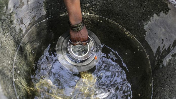 A woman fetches water from a small tank outside her house in Beed district, Maharashtra| Photo: Dhiraj Singh/Bloomberg