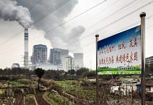 A sign warning local residents not to burn trash in order to reduce pollution stands in a field as emissions rise from cooling towers at a coal-fired power station in Tongling, Anhui province, China. | Photographer: Qilai Shen | Bloomberg