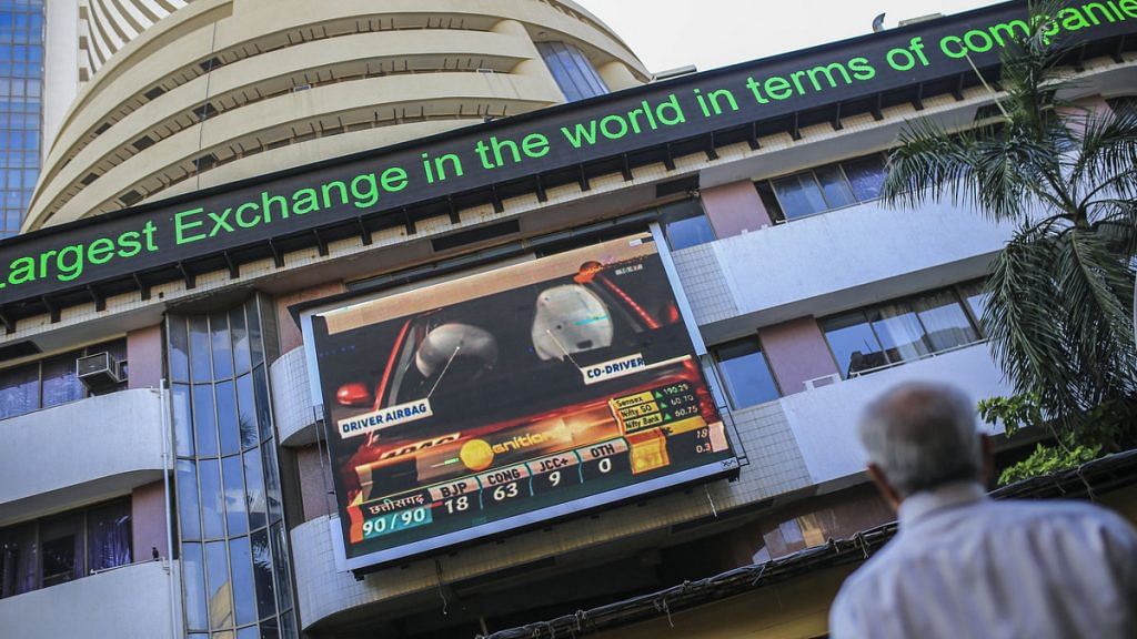 A man looks toward a screen and an electronic ticker board outside the Bombay Stock Exchange (BSE) building in Mumbai| Photo: Dhiraj Singh/Bloomberg