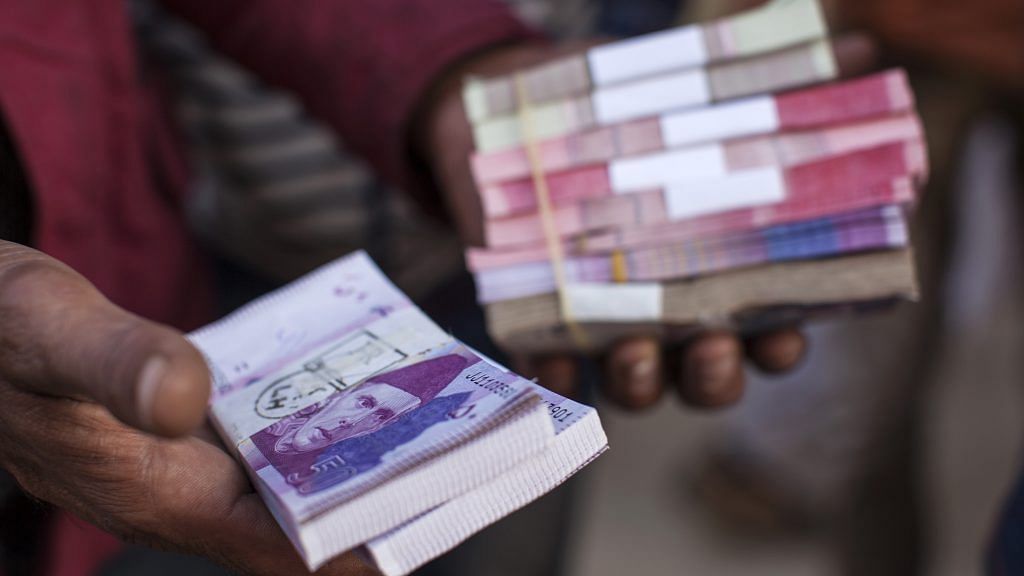 A roadside money changer handles bundles of Pakistani rupee banknotes at a currency exchange market in Pakistan. | Photographer: Asim Hafeez | Bloomberg