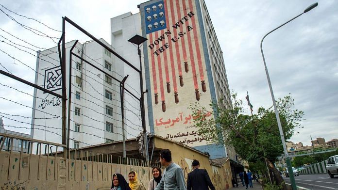 Pedestrians pass a giant wall mural proclaiming 'Down With The USA' on a street in Tehran, Iran | Ali Mohammadi/Bloomberg