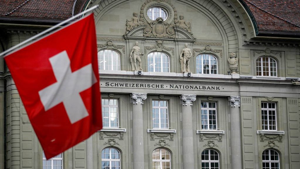 A Swiss national flag hangs in view of the Swiss National Bank (SNB) in Bern, Switzerland