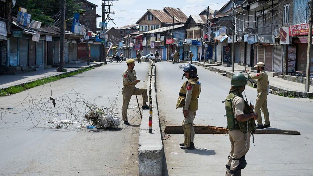 Security personnel stand guard at a check point during restrictions in Sringar
