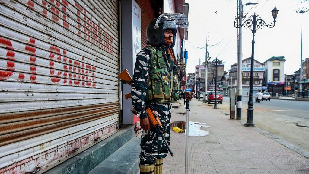 A security personnel stands guard outside closed shops, in Srinagar