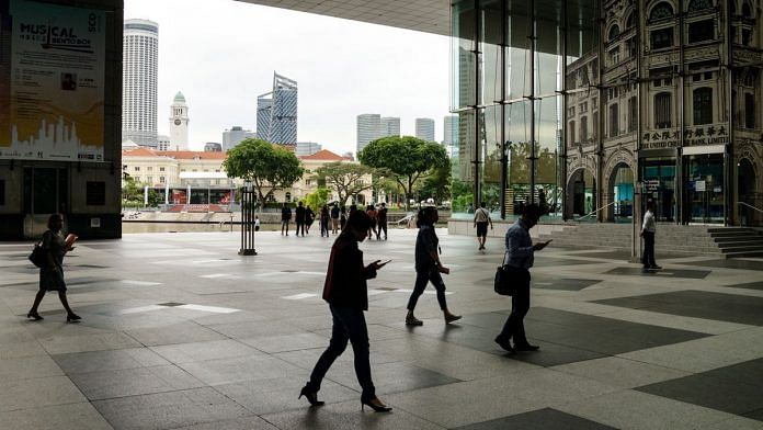 Pedestrians walk in front of the office buildings in the central business district in Singapore. | Photo: Sanjit Das | Bloomberg