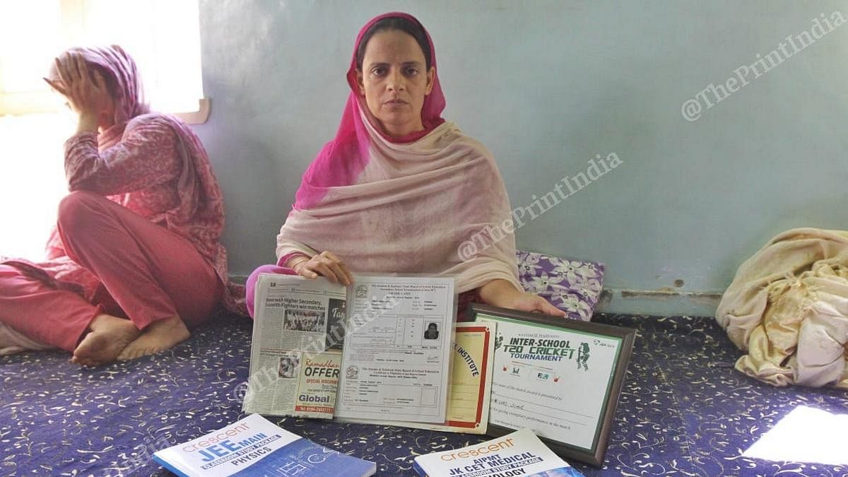 Asrar's mother holding up his certificates and marksheets