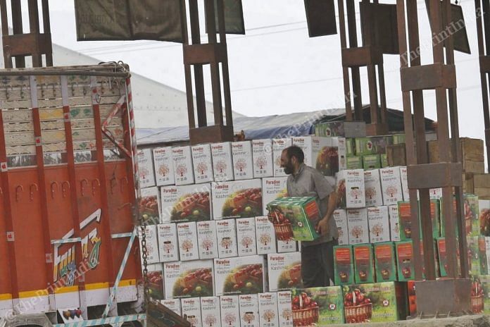 A man stacks packed apples into trucks at the Sopore apple market. | Photo: Praveen Jain | ThePrint