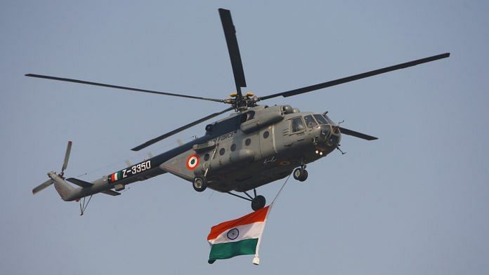 An Indian Air Force military helicopter displays an Indian flag as it flies past during the Republic Day Parade | Bloomberg