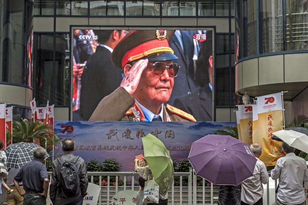 People watch a large screen showing a live broadcast of the military parade for the 70th anniversary of the People's Republic of China in Shanghai, China, on Tuesday, Oct. 1, 2019. President Xi Jinping declared that no force could stop Chinas rise, exuding confidence during a key anniversary as he faced | Photo by Qilai Shen | Bloomberg