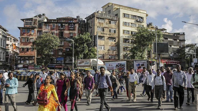Commuters cross a road near Chhatrapati Shivaji Maharaj Terminus railway station in Mumbai