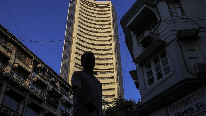 A pedestrian is silhouetted as the Bombay Stock Exchange (BSE) building, center, stands the background in Mumbai. | Photo: Dhiraj Singh| Bloomberg