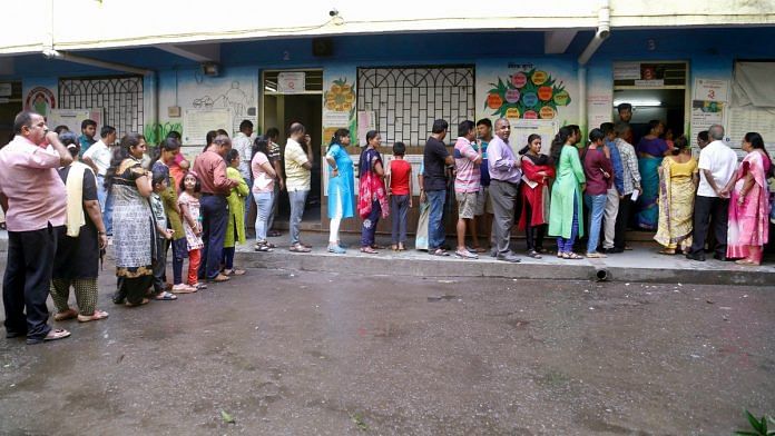 Voters stand in a queue displaying their voter card outside a polling station during Maharashtra Assembly elections in Thane | PTI