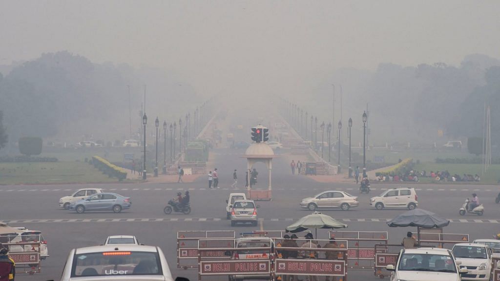Vehicles ply on Rajpath shrouded in smog, in New Delhi