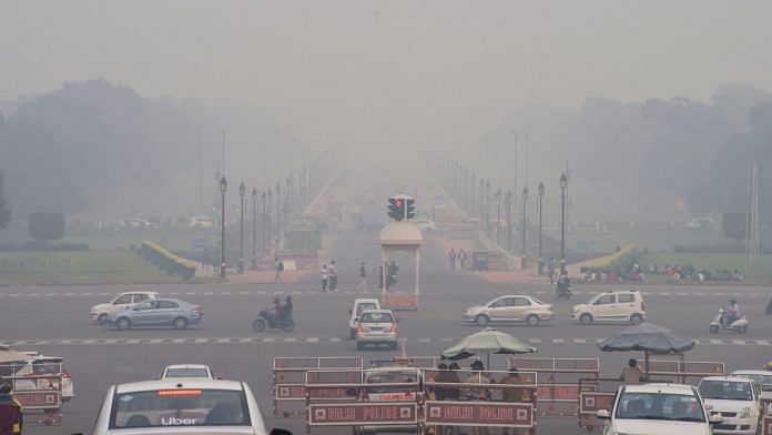 Vehicles ply on Rajpath shrouded in smog, in New Delhi