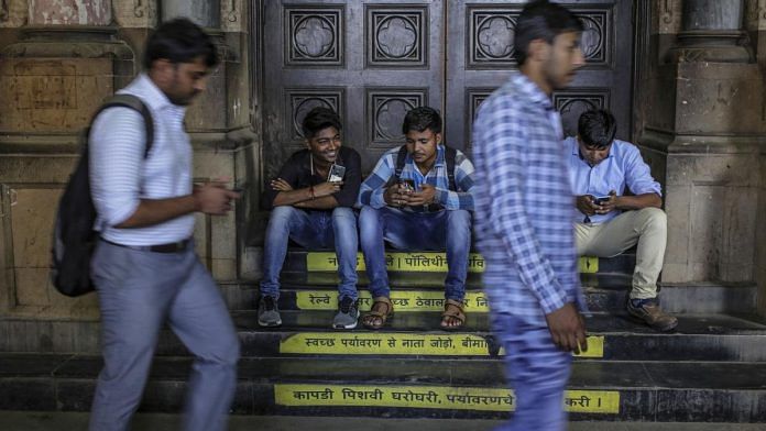 Commuters sitting outside Chhatrapati Shivaji Maharaj Terminus train station in Mumbai
